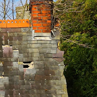 Dilapidated roof with brick chimney and ivy