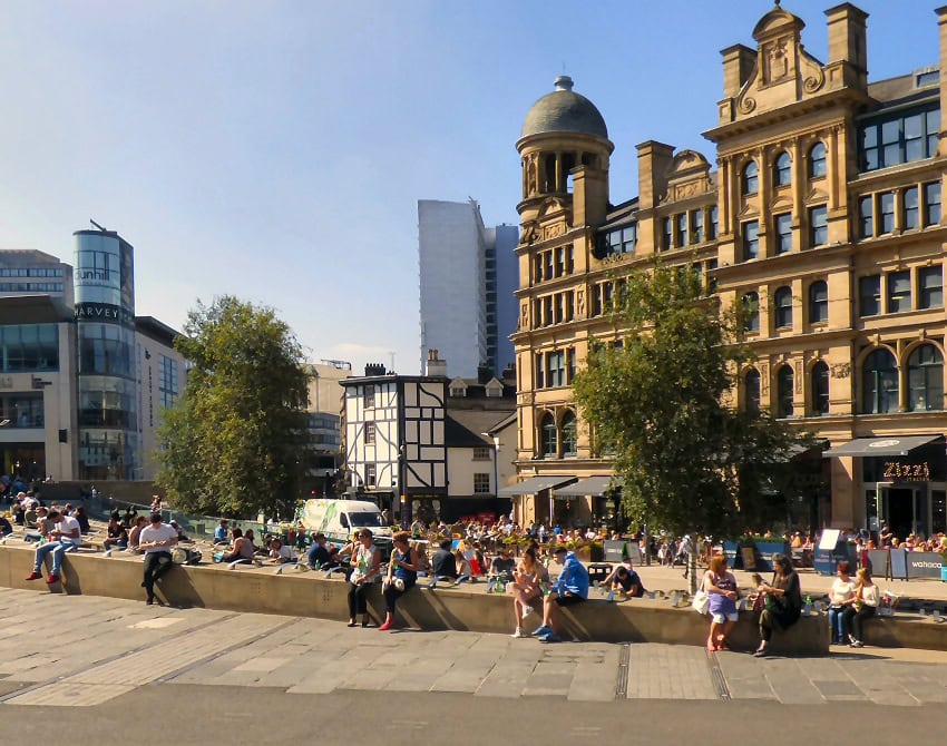 Sunny day in urban plaza with historic buildings.