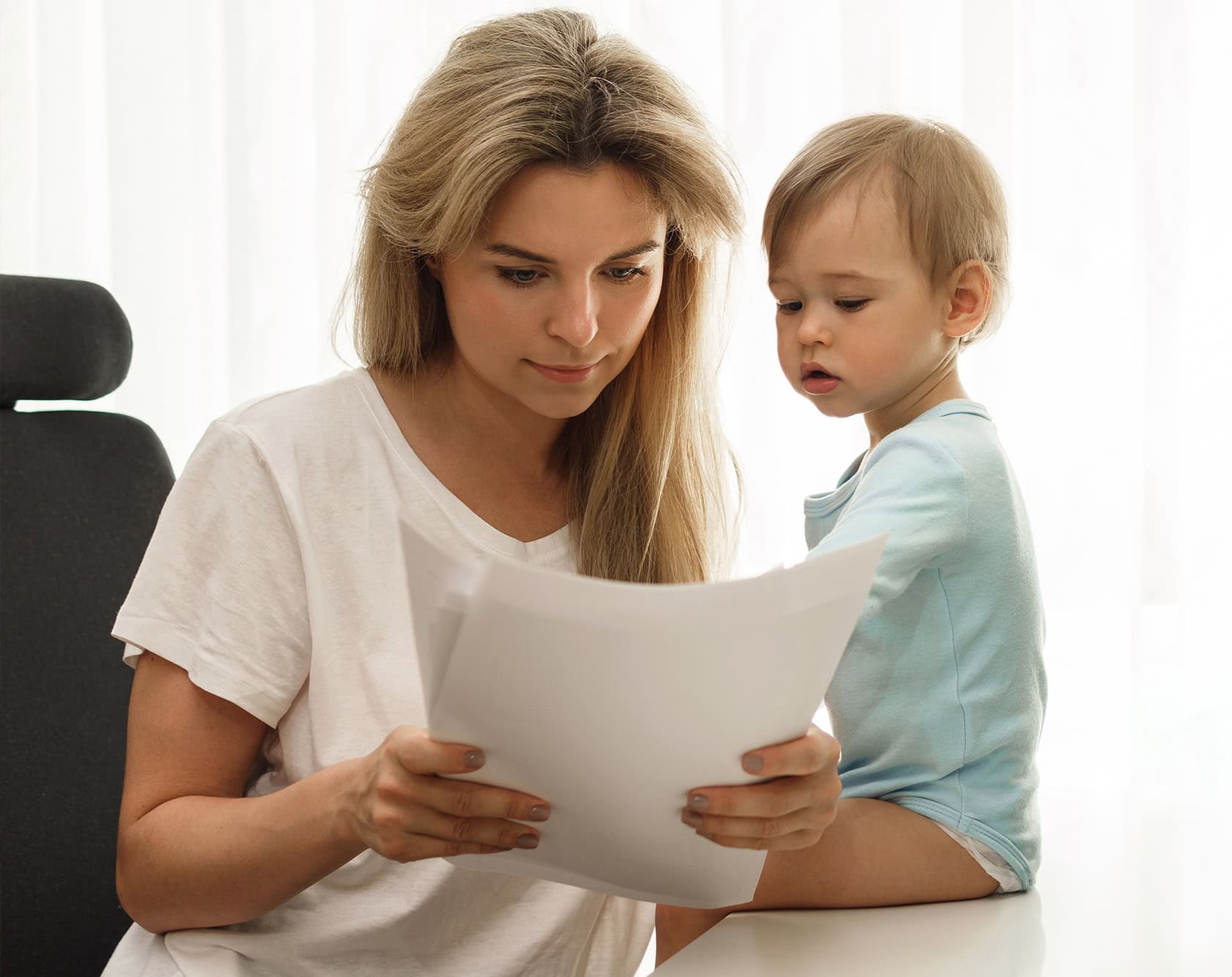 Woman reading housing disrepair claim with child on lap.